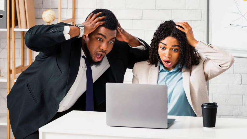 Black colleagues looking at laptop screen in terror, finding mistake in business project at modern office
