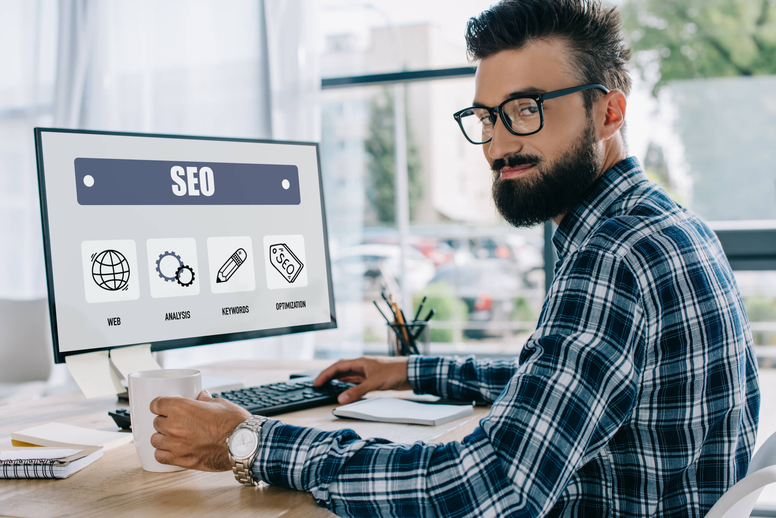 young successful seo manager sitting at workplace with computer and looking at camera - Jummp Marketing
