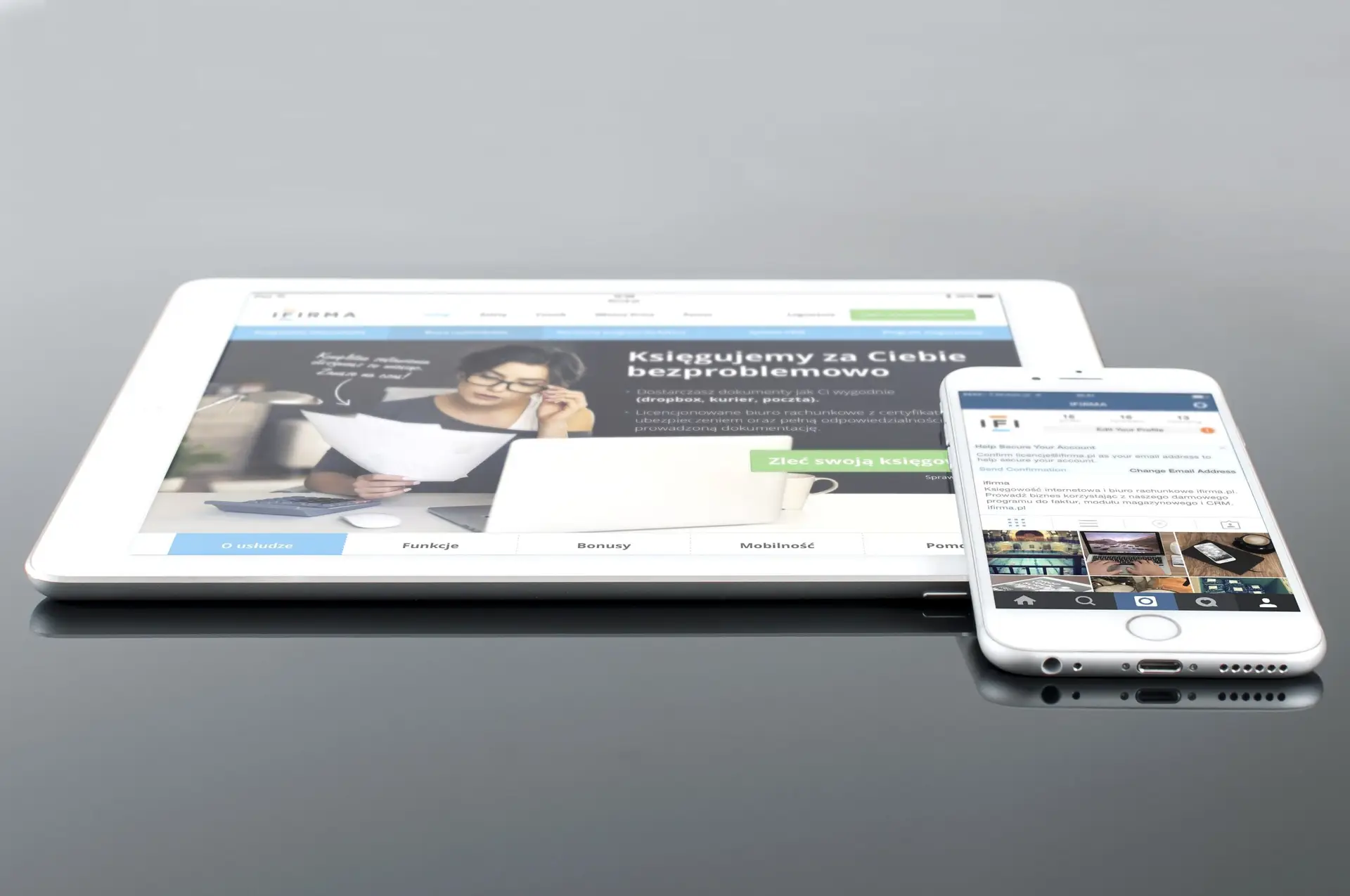 Modern tablet and smartphone displaying web content on a reflective surface, highlighting technology and connectivity.