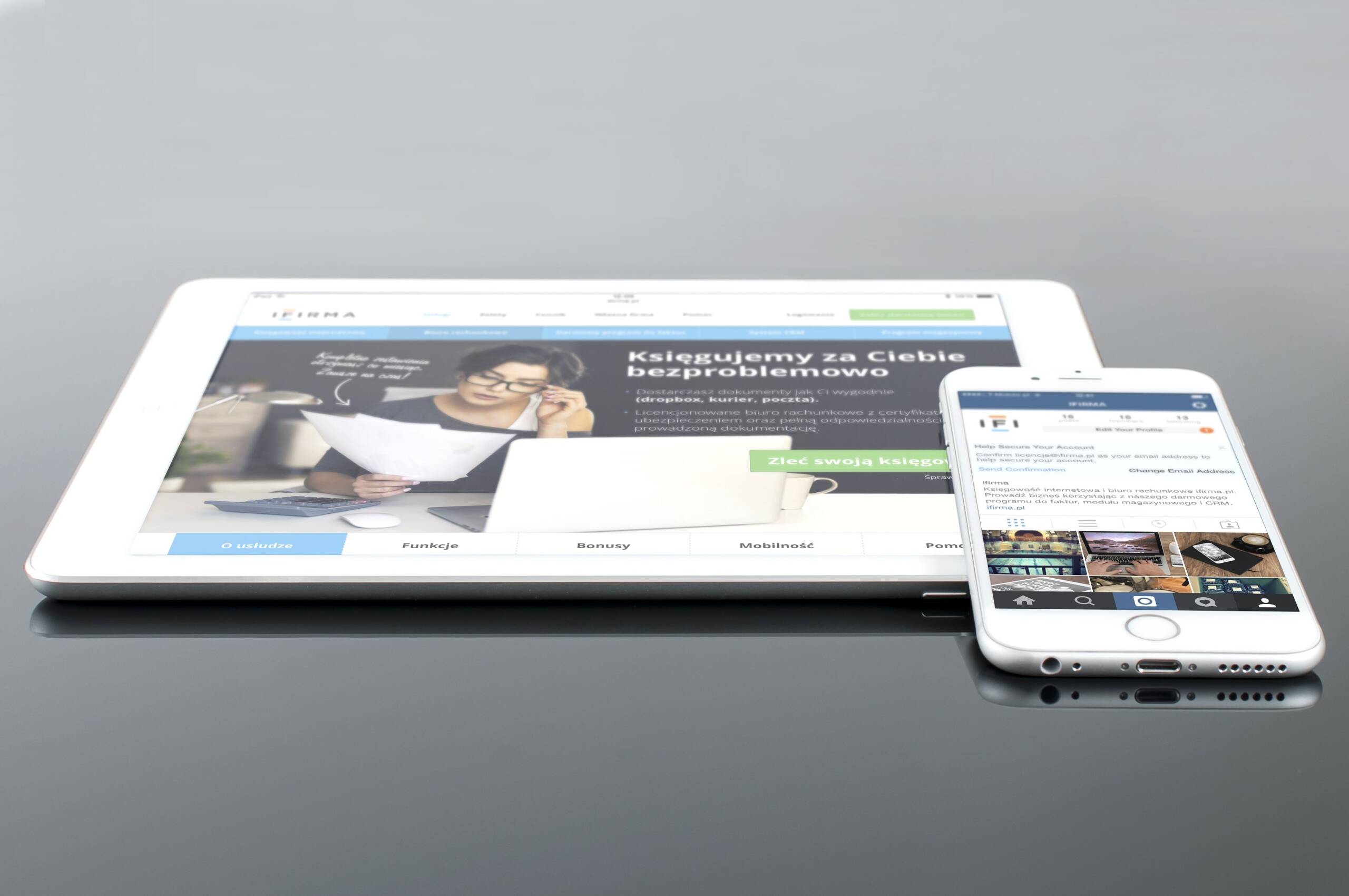 Modern tablet and smartphone displaying web content on a reflective surface, highlighting technology and connectivity.